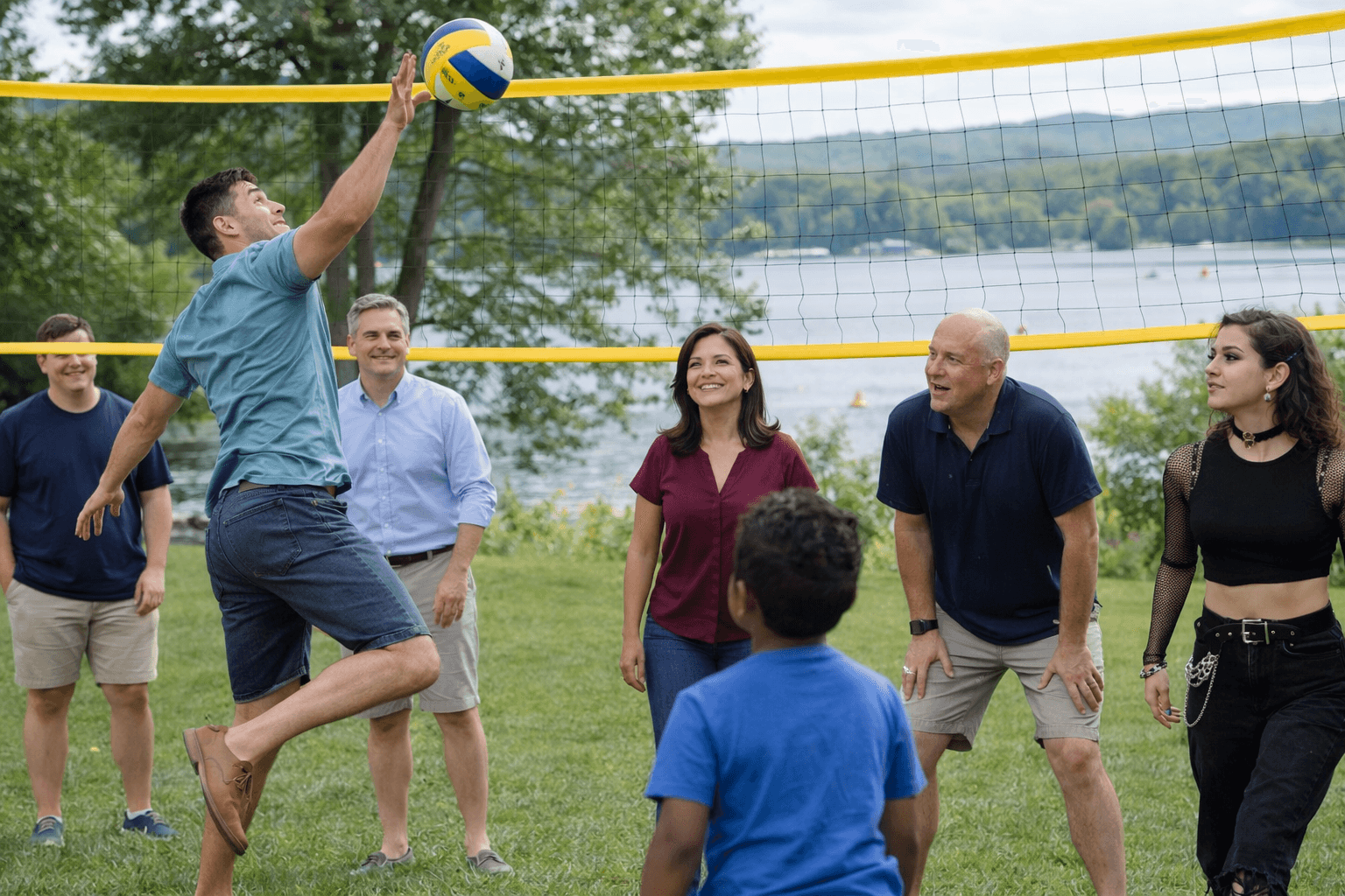 Team playing volleyball at a company picnic by the lake